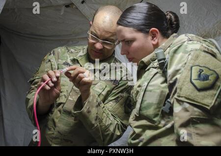 Sgt. Ryan Davis, una tecnologia di informazione non ufficiale incaricato con la manovra 158Brigata Enhancement, mostra PFC. Marissa Newman, un FM communications specialist, la configurazione dei pin per fissare un cavo Ethernet. I soldati sono state conducendo addestramento annuale presso il Camp Navajo, Ariz., Giugno 3-17 in preparazione di un imminente Warfighter esercizio entro la fine di quest'anno. (Ariz. Esercito Foto Stock