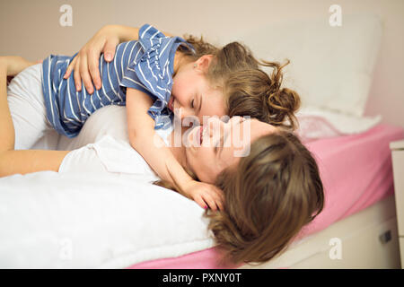 Madre e figlia godono nel letto di casa Foto Stock