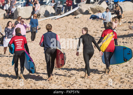 Navigare in Cornovaglia - Istruttori di Surf da Fistral Beach Surf School che trasportano le loro tavole da surf a Fistral a Newquay in Cornovaglia. Foto Stock