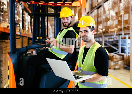 Magazzinieri lavorando insieme con il carrello caricatore Foto Stock