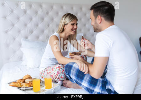 Giovane coppia attraente avente la colazione a letto Foto Stock