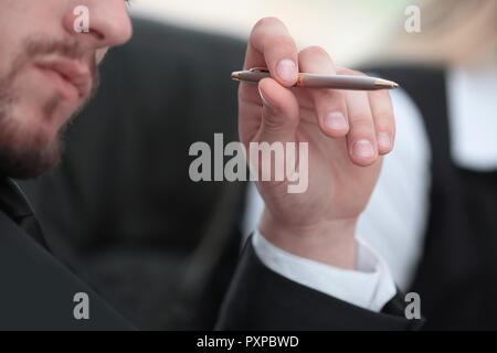 Close up. pensieroso imprenditore con penna seduta a tavola Foto Stock