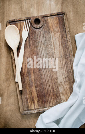 Sfondo di cucina: Rustico posate con carta asciugatutto o tovagliolo sulla tavola di legno sopra la tavola in legno rustico. Vista da sopra con lo spazio di copia Foto Stock