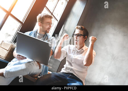 I Creative avente una riunione informale a un tavolo in studio di design. Colpo di professionisti di aziende aventi una riunione in ufficio. Foto Stock