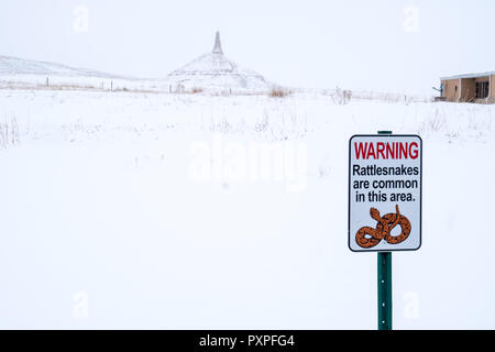 Segno di avvertimento circa visitatori rattlesnakes in Chimney Rock National Historic Site lungo la Oregon Trail. Foto scattata durante una tempesta di neve in inverno Foto Stock