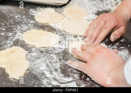 Mani lavorazione dell'impasto su una superficie infarinata. Foto Stock