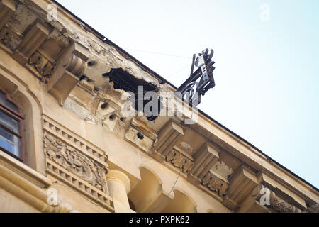 Rotture di facciata di un vecchio (interbelic periodo) edificio, lasciati a marcire. Mobilio ascensore sul tetto Foto Stock