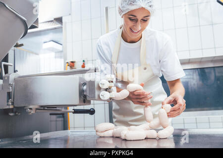 Donna fare salsicce in macelleria Foto Stock