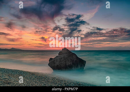 Una lunga esposizione photograhy al rocky Kato Petres paesaggio sulla spiaggia al tramonto. Rhodes, Grecia Foto Stock