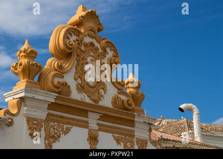 Parte anteriore del tetto di una casa con la facciata bianca ornate con decorazioni in giallo. Tipica architettura portoghese. Camino bianco accanto ad esso sul r Foto Stock