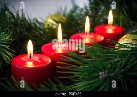 Quattro rosso illuminato avvento candele circondato dal verde abete rami Foto Stock