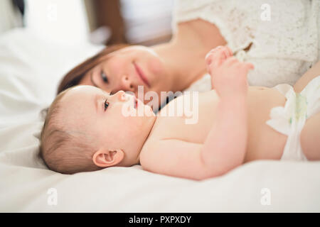 La madre gioca con il suo bambino in camera da letto Foto Stock