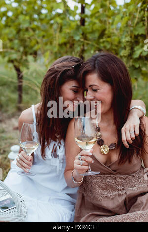 Amici a picnic estivo in un vigneto, bere vino Foto Stock