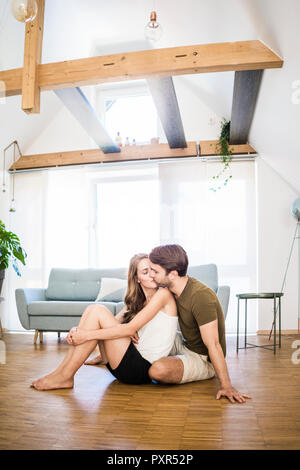 Coppia affettuoso bacio sul pavimento a casa Foto Stock