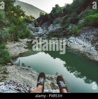 L'Italia, Marche, Fossombrone, Marmitte dei Giganti canyon, il fiume Metauro, escursionista seduta su Riverside, scarpe Foto Stock