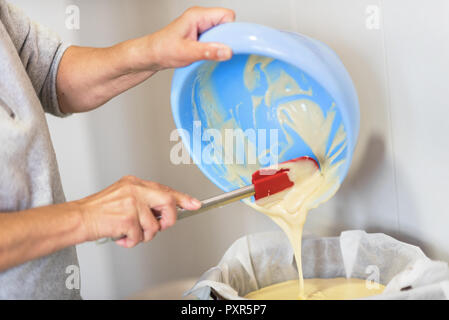 Senior Mani donna versando l'impasto in un vassoio da forno. Shallow profondità di campo. Foto Stock