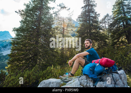 Austria, Tirolo, Escursionista prendendo una pausa, seduto su una roccia Foto Stock