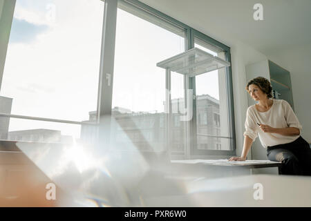 Imprenditrice lavoro in ufficio, seduto sulla scrivania Foto Stock