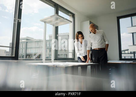 Due architetti che lavorano in ufficio, discutendo blueprints Foto Stock