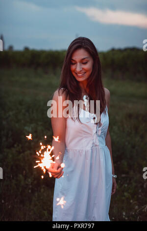 Giovane donna in natura, burning sparkler di sera Foto Stock