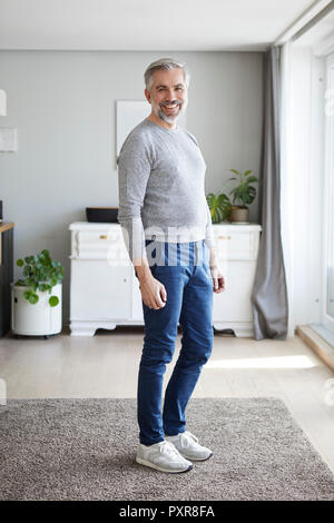 Ritratto di sorridere uomo maturo in piedi nel suo salotto Foto Stock