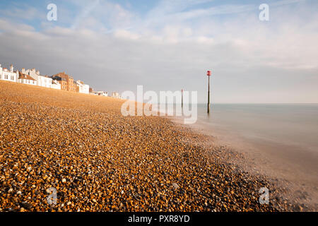 La mattina presto luce sulla spiaggia di ciottoli a trattare, Kent, Regno Unito. Le case lungo Beach Street sono visibili e ci sono i marcatori di marea in mare. Foto Stock
