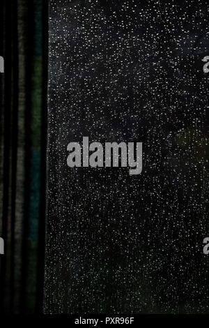 Le gocce di pioggia sul vetro di finestra visto dall'interno Foto Stock
