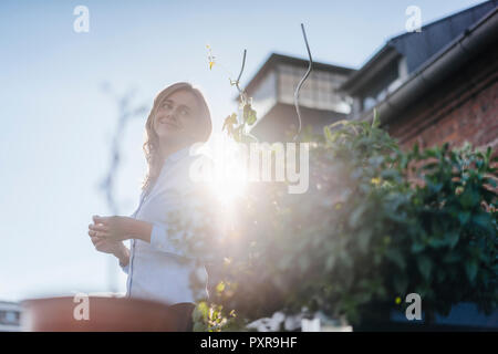 Imprenditrice permanente sulla sua urbano giardino sul tetto Foto Stock