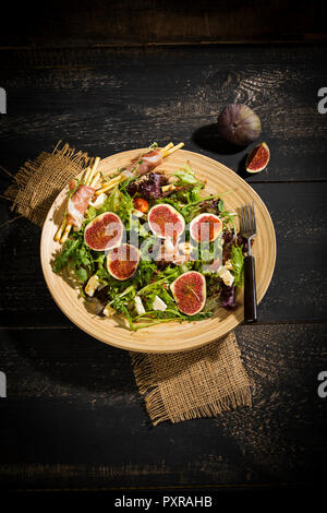 Insalata mista con fichi, pomodori, formaggio di pecora, grissini con prosciutto sulla piastra bambus Foto Stock