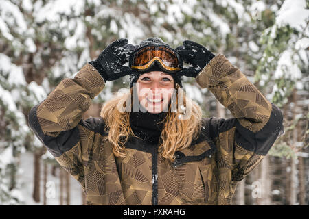 Ritratto di felice giovane donna in skiwear nella foresta di inverno Foto Stock