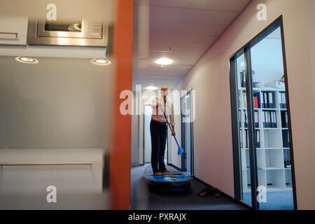 Imprenditore permanente sulla scheda paddle, esercitando nel corridoio di office Foto Stock