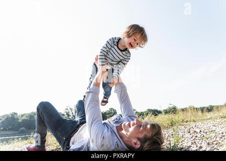 Padre e figlio divertendosi al Riverside, riproduzione di aeroplano Foto Stock