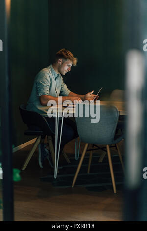 Uomo seduto in ufficio, lavora fino a tardi nella sua azienda start-up Foto Stock