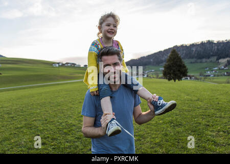 Austria, Tirolo, Walchsee, felice padre figlia portante trasportato su un prato alpino Foto Stock