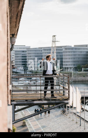 Imprenditore in piedi sul balcone, muscoli di flessione Foto Stock