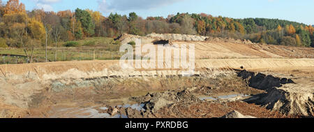 Un grande colline e cave di sabbia e tracce di un bulldozer pesanti e trattori su una foresta di autunno sito in costruzione. Collage panoramico da diversi fuori Foto Stock