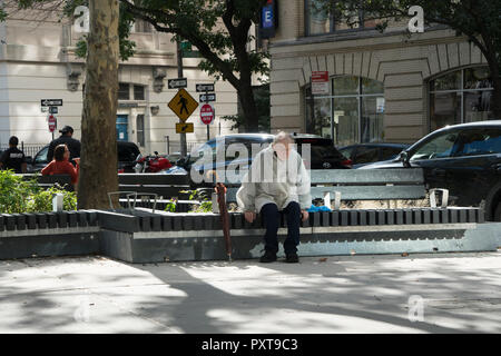 Un uomo anziano con un ombrello sat da soli in Spring Street Park in una giornata di sole in ottobre. Il parco che è appena al di sotto di un acro di dimensione, è sud Foto Stock