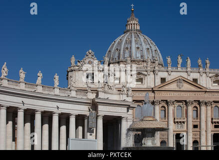 La Basilica di San Pietro in Vaticano, che mostra parte del colonnato disegnata dal Bernini e la facciata e la cupola della basilica contro un Cielo di estate blu Foto Stock