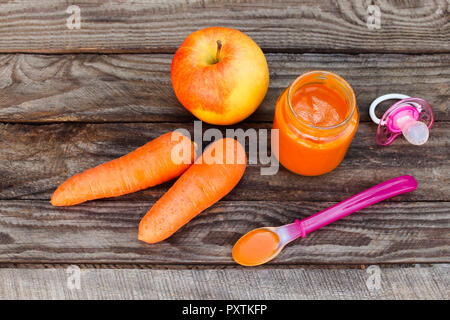 Purea di frutta, carota, Apple e il succhietto su sfondo di legno Foto Stock