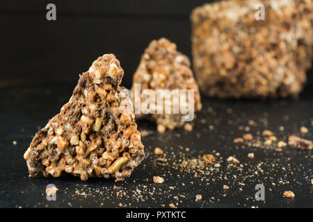 Pezzi di massa di cioccolato con riso soffiato e uva passa su sfondo scuro con spazio di copia Foto Stock