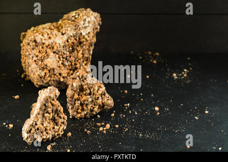 Pezzi di massa di cioccolato con riso soffiato e uva passa su sfondo scuro con spazio di copia Foto Stock