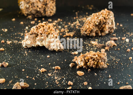 Cioccolato con riso soffiato e uvetta con pasticcini su sfondo scuro Foto Stock