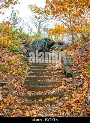 Vecchio abbandonato e la scala disseminata di caduta foglie secche in autunno park Foto Stock
