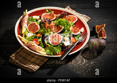 Insalata mista con fichi, pomodori, formaggio di pecora, grissini con prosciutto sulla piastra Foto Stock