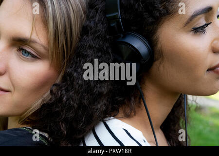 Due amiche in un parco e ascolto di musica Foto Stock