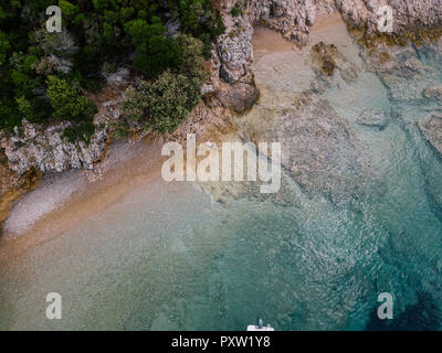 Croazia, Cres, Mare Adriatico, uomo disteso sulla spiaggia rocciosa, vista aerea Foto Stock