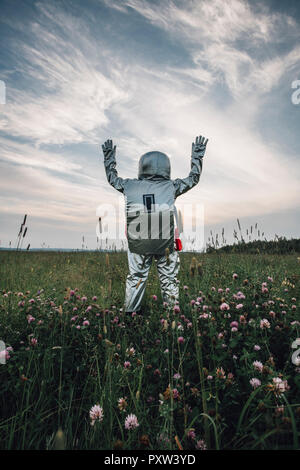 Spaceman esplorando la natura, in piedi nel prato, sventolando Foto Stock