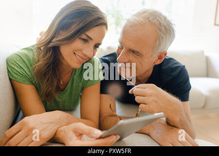 Sorridente Coppia matura sdraiato sul lettino a Condivisione in famiglia tablet Foto Stock