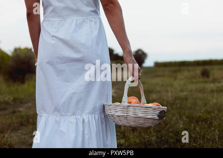 La donna a piedi vigneto portando un cestino picnic Foto Stock