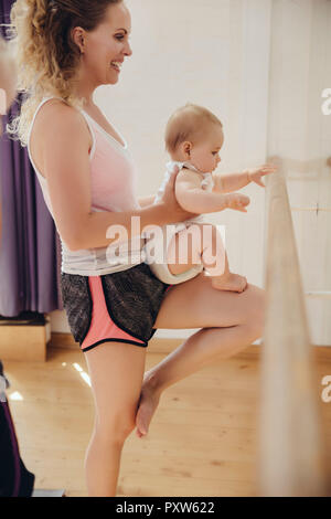 Due mamme con i loro bambini piccoli a barre in studio di danza Foto Stock